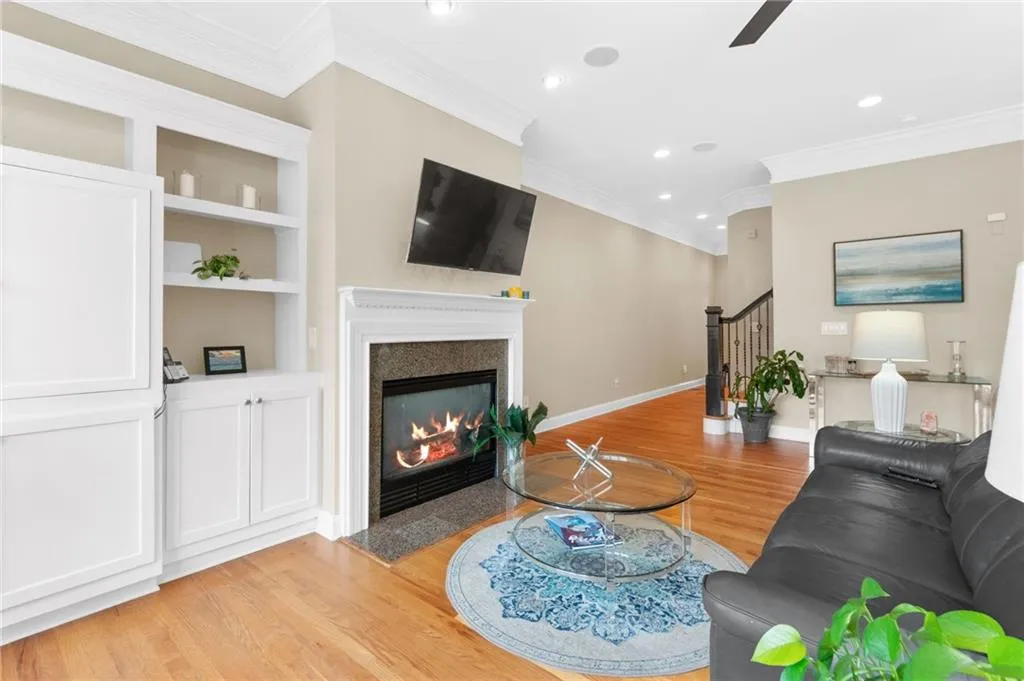 Living area with light wood-style flooring, a fireplace with flush hearth, recessed lighting, ceiling fan, and built in shelves
