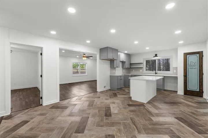Kitchen featuring gray cabinets, a kitchen island, tasteful backsplash, a ceiling fan, and parquet floors