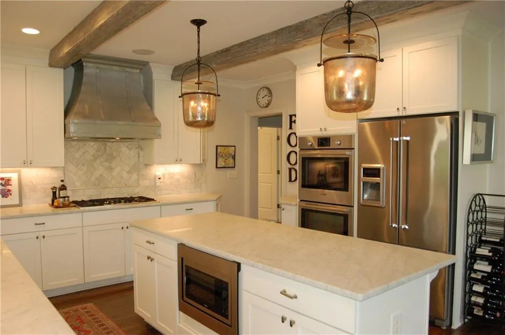 Custom hood, white shaker style cabinets, stainless steel appliances, upgraded lighting and faux beams.