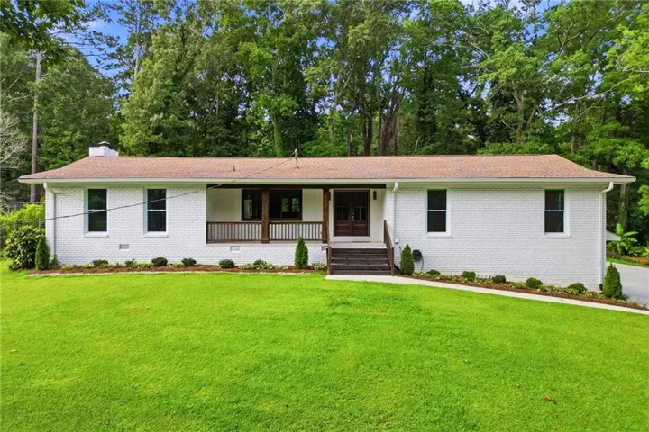 White brick exterior with a welcoming covered porch, dark wood columns, and a matching railing