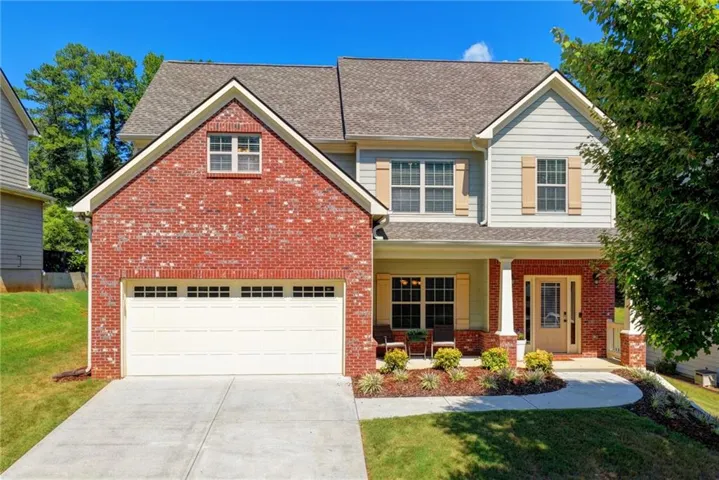Brick and siding exterior with a covered front porch, attached garage, and a concrete driveway
