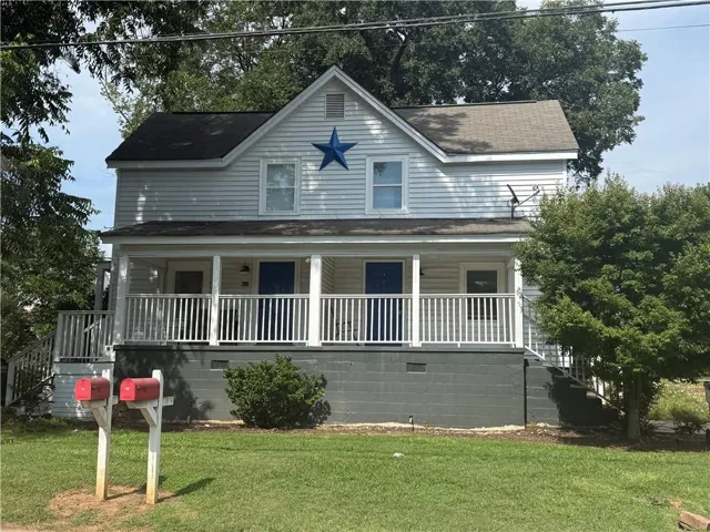 Two-story exterior with white siding, covered porch, and dual entry doors