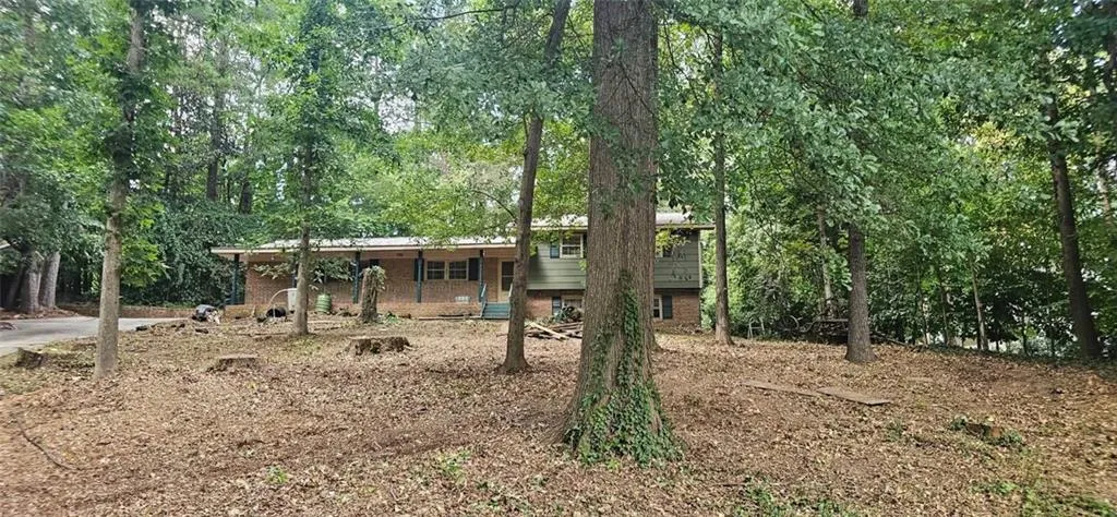 Expansive wooded lot with mature trees, brick and siding exterior, front porch, and multi-level architectural style