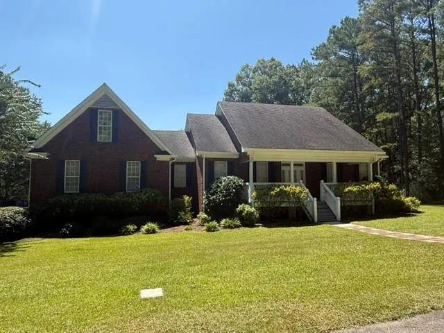 Brick facade with white trim, covered front porch, and dormer window