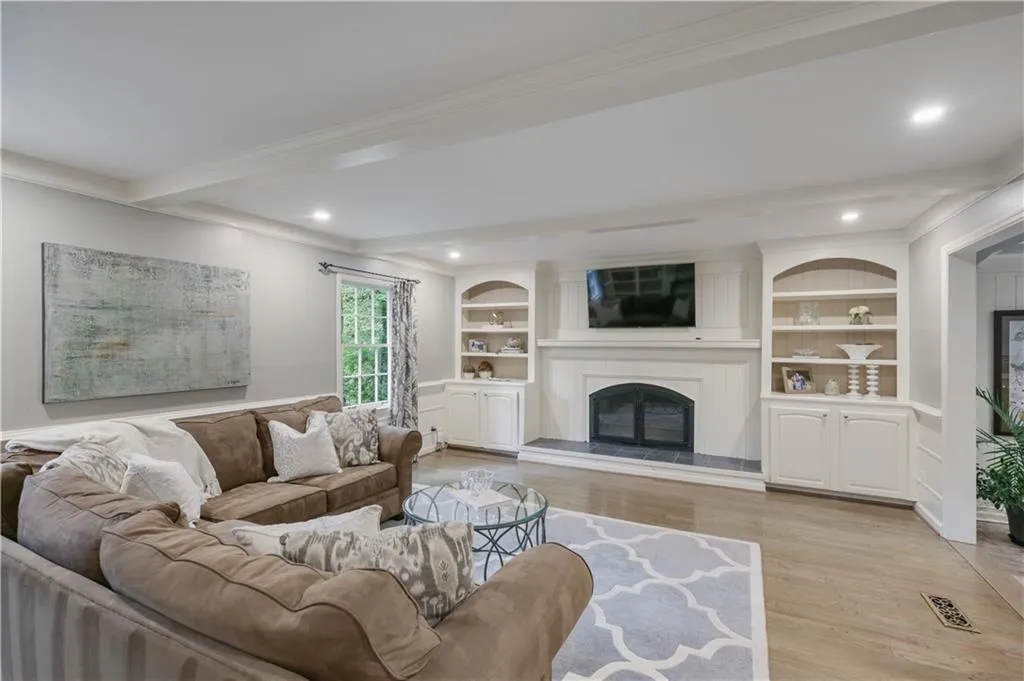 Living room featuring beamed ceiling, built ins, wet bar and fireplace