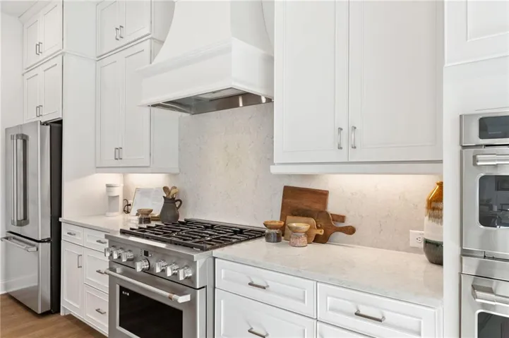 Kitchen features a beautiful vent hood and quartz countertops.