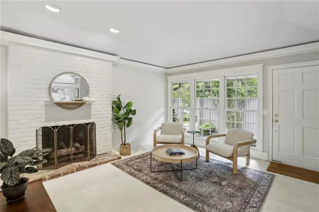 A cozy fireplace framed by exposed brick is the focal point of the home. Recessed lighting casts a soft glow, enhancing the natural light streaming in from the large windows—ideal for relaxation and entertaining.