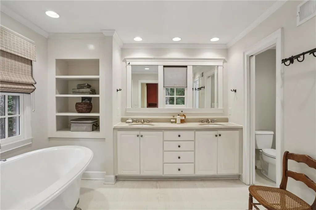 Double vanity and soaking tub with private toilet closet, provides a restful space to get ready. Notice the ample recessed lighting and cozy built-ins.