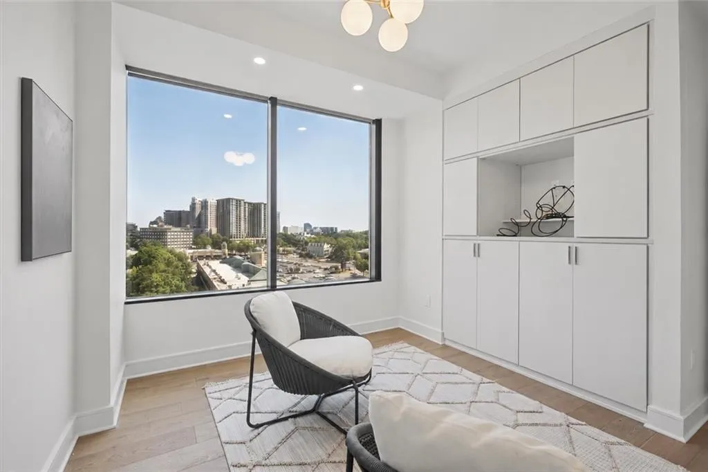 Expansive window with city scenery, built-in cabinetry with open shelving, wood-finish flooring, and recessed lighting