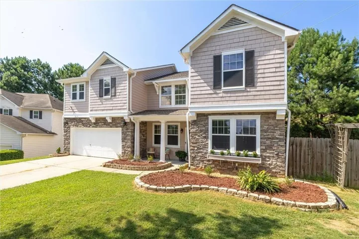 Two-story home with a stone and shingle facade, featuring a prominent front-facing garage