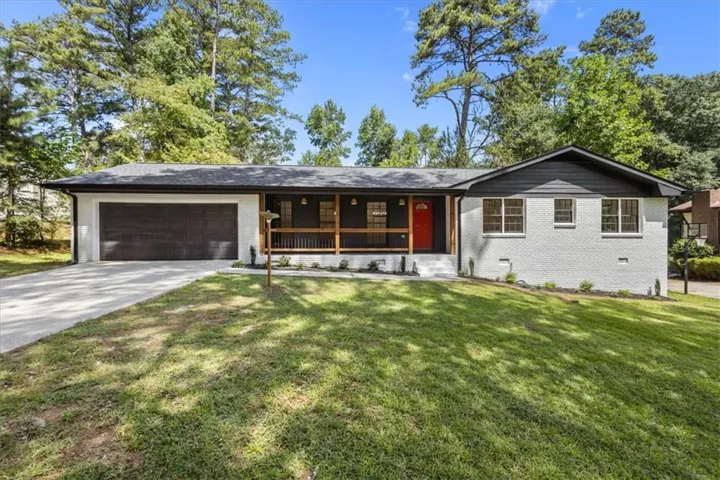 Ranch-style residence featuring a white painted brick facade and a dark gray roof