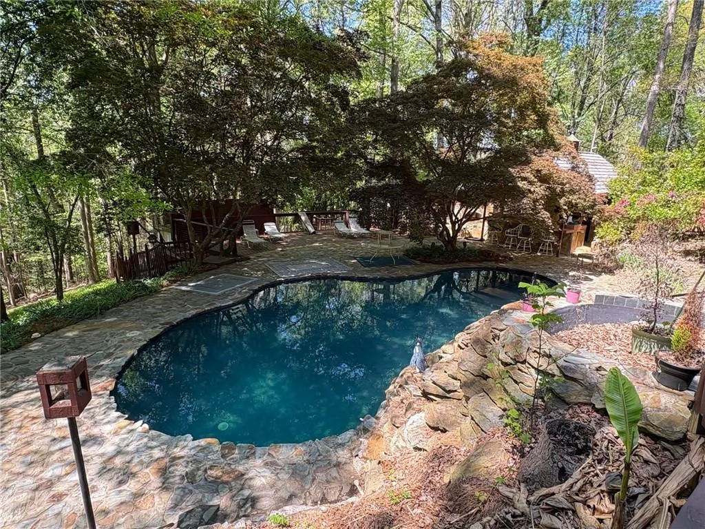 Outdoor pool with a patio and view of wooded area