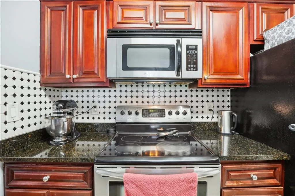Kitchen featuring backsplash, dark stone countertops, and appliances with stainless steel finishes