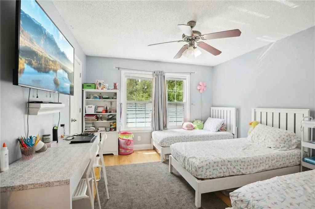 Bedroom featuring ceiling fan, light hardwood / wood-style floors, and a textured ceiling