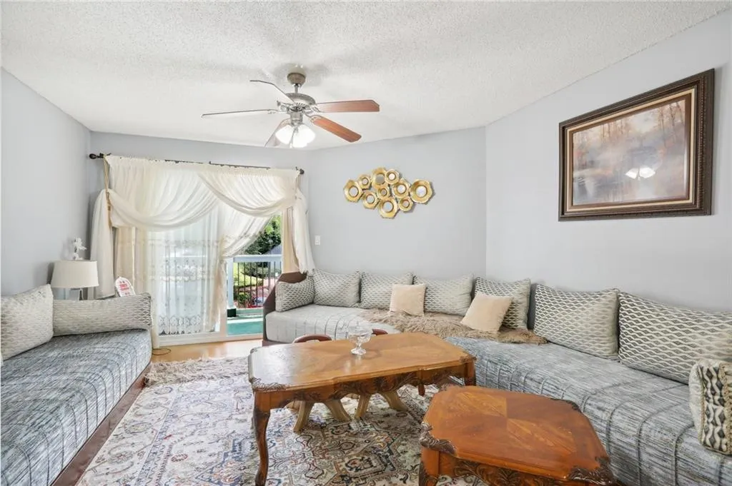Living room with ceiling fan, hardwood / wood-style flooring, and a textured ceiling
