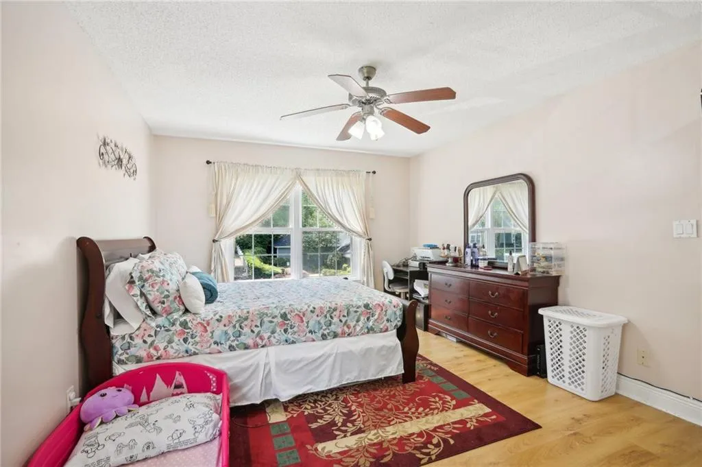 Bedroom with ceiling fan, light hardwood / wood-style flooring, and a textured ceiling