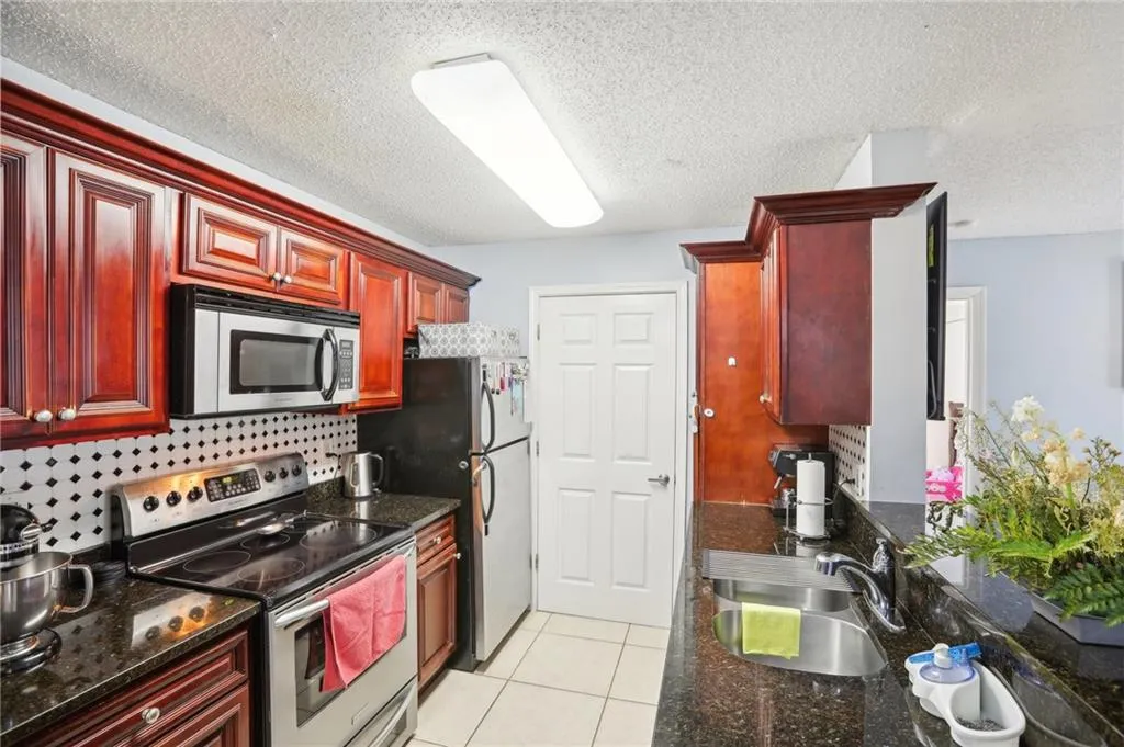 Kitchen with stainless steel appliances, sink, backsplash, and light tile floors