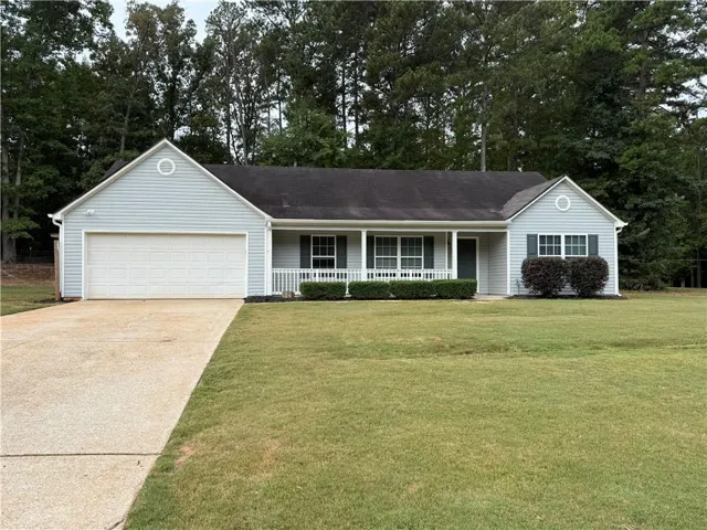 Ranch-style residence featuring light blue siding, a covered front porch with white railing, and a two-car garage