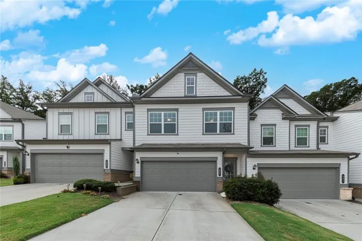 Exterior featuring white siding, dark gray trim, multiple gables, and individual garages