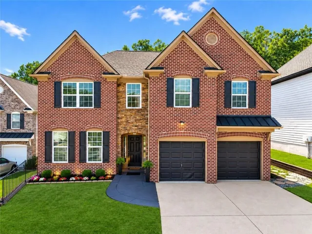 Striking brick Colonial featuring a symmetrical facade with multiple gabled rooflines, black shutters, and an arched entryway
