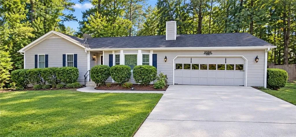 Ranch-style exterior with gray siding, dark blue shutters, a dark roof, and a two-car garage