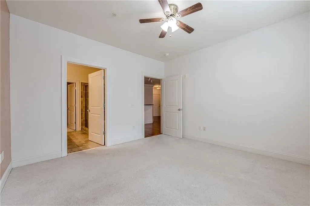 Unfurnished bedroom featuring light carpet and ceiling fan