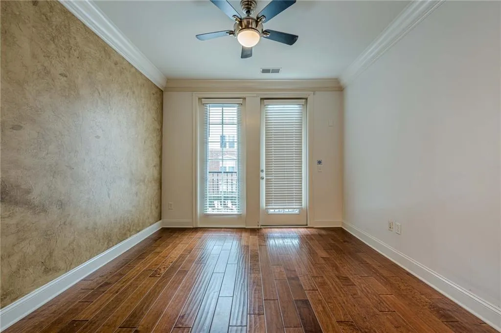 Spare room featuring crown molding, hardwood / wood-style flooring, and a ceiling fan