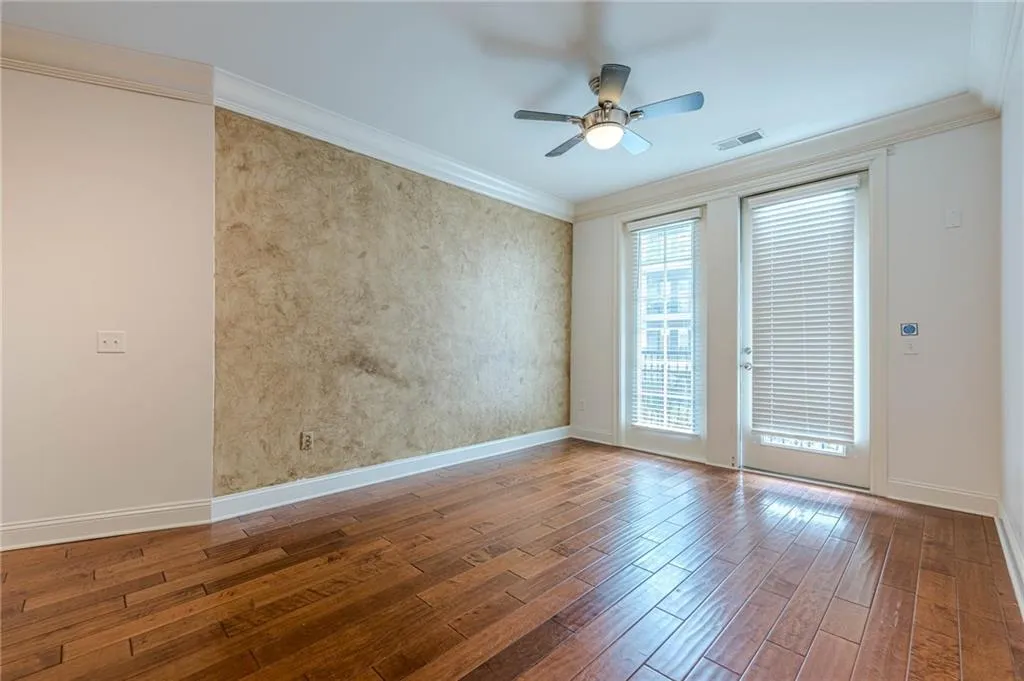 Empty room featuring wood finished floors, crown molding, and a ceiling fan