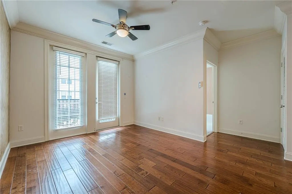 Spare room with dark wood finished floors, crown molding, and ceiling fan