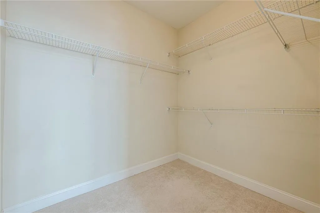 Walk in closet featuring light colored carpet