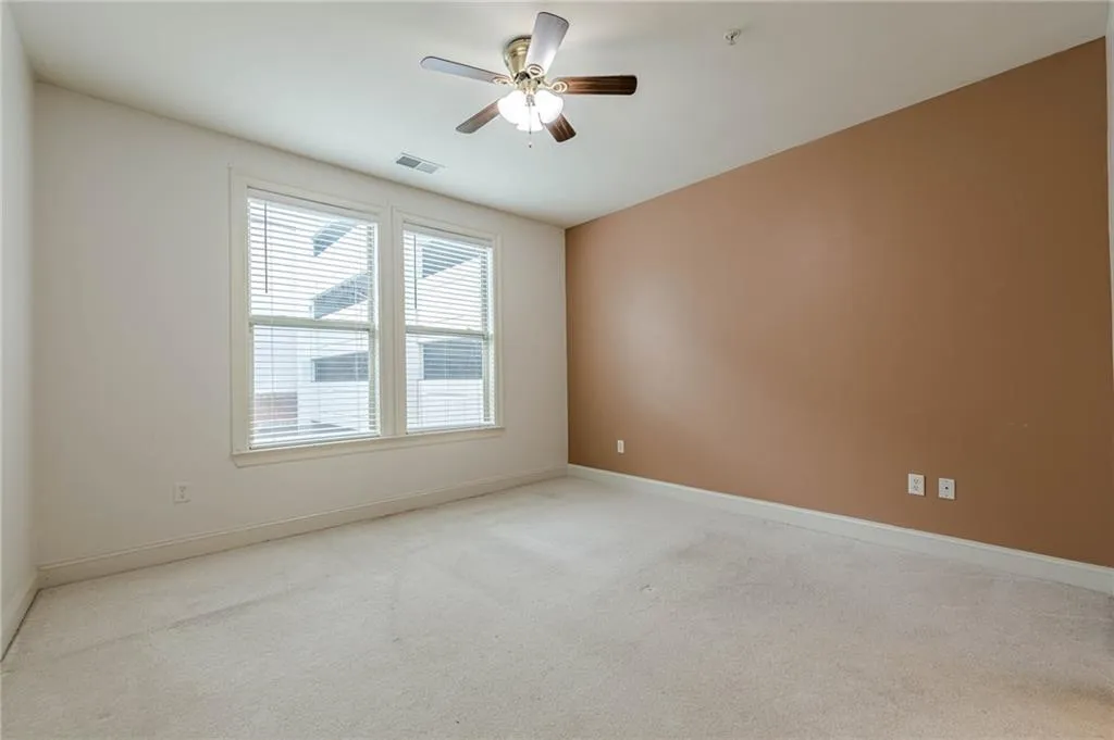 Empty room featuring light carpet and a ceiling fan