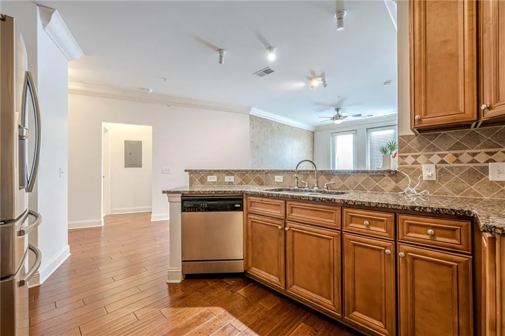 Kitchen featuring brown cabinets, backsplash, stainless steel appliances, crown molding, and a peninsula