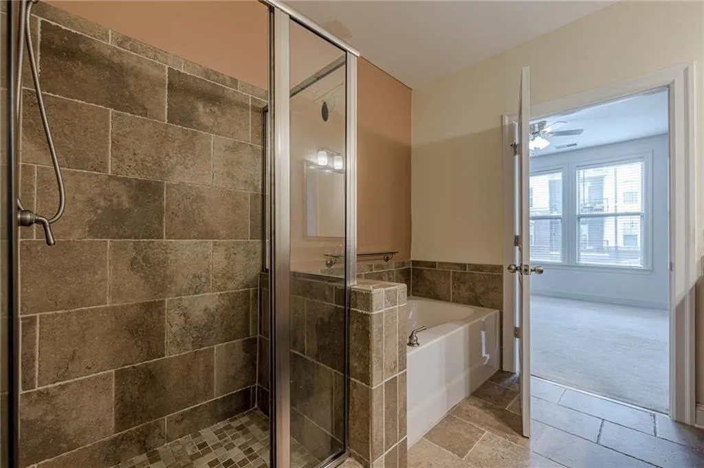 Full bath with a bath, a shower stall, tile patterned flooring, a ceiling fan, and carpet