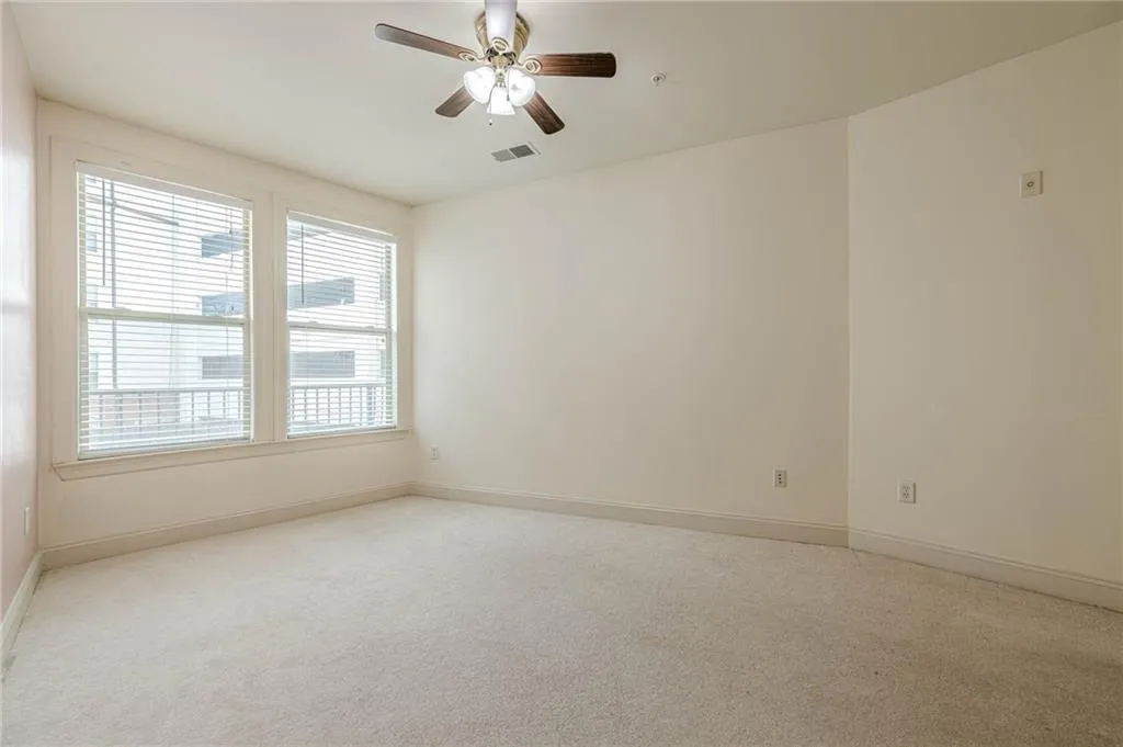 Empty room with light colored carpet and a ceiling fan