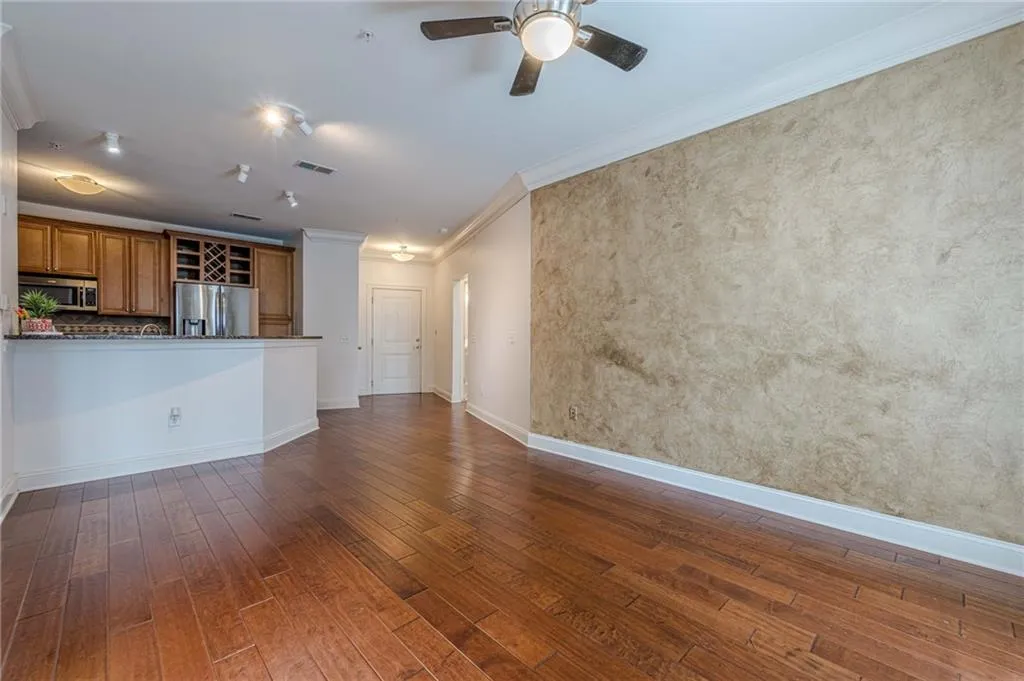 Unfurnished living room featuring crown molding, dark wood-type flooring, and ceiling fan