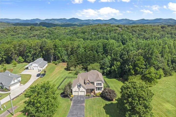 Aerial perspective showcasing a property with a distinct roofline, a two-car garage, and a paved driveway