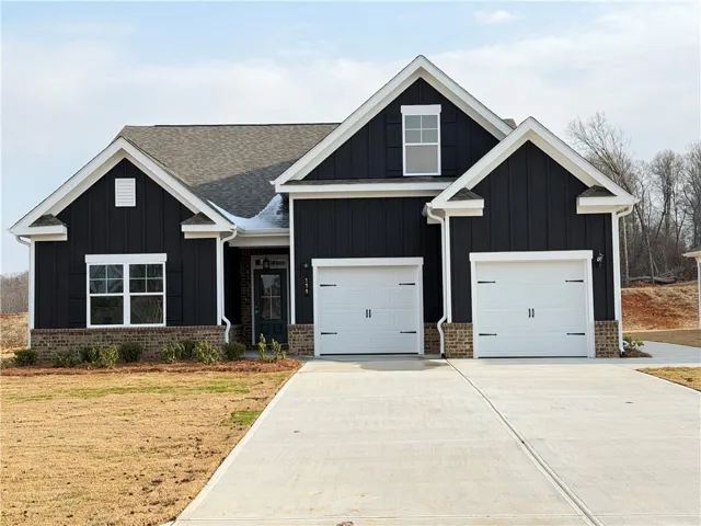 Modern inspired home with board and batten siding, concrete driveway, and brick siding