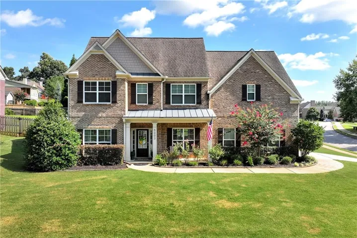 Brick and siding exterior with a covered entry, mature landscaping, and a manicured lawn