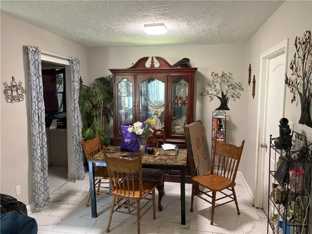 Dining area featuring light-toned walls, white tile flooring, and a flush-mount ceiling light