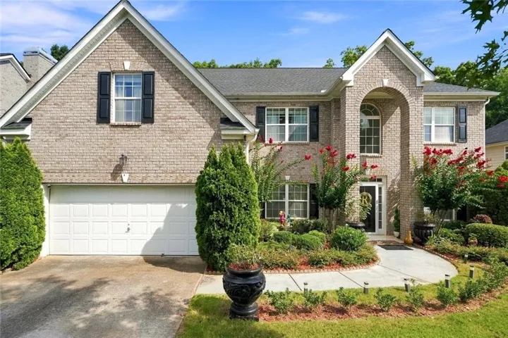 Brick exterior with an arched entry, prominent gables, and a two-car garage
