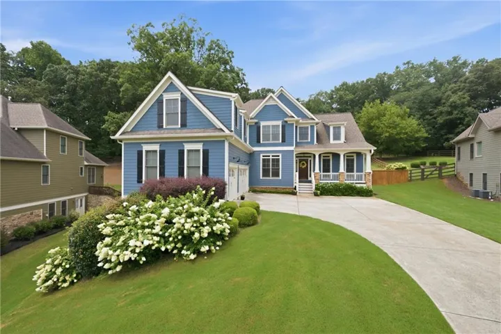 Blue siding exterior featuring white trim, dark shutters, and a covered front porch with stone accents
