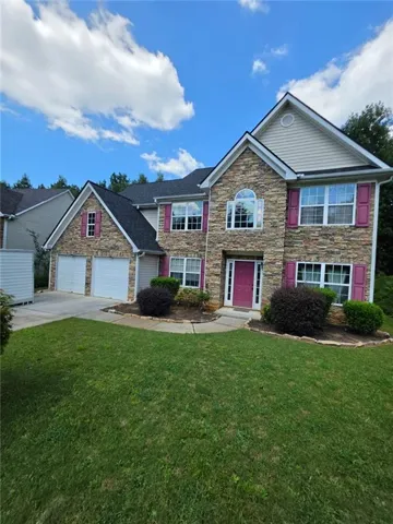 Stone and siding exterior with a two-car garage, front entry, and mature landscaping