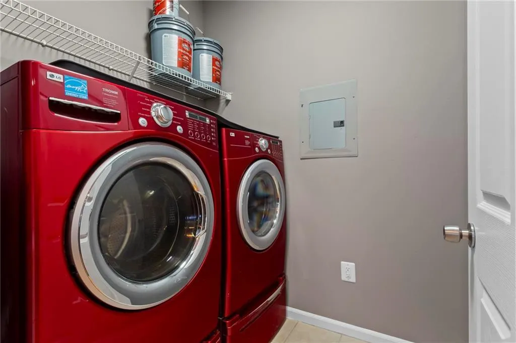 Washroom with electric panel, washer and clothes dryer, and light tile patterned flooring