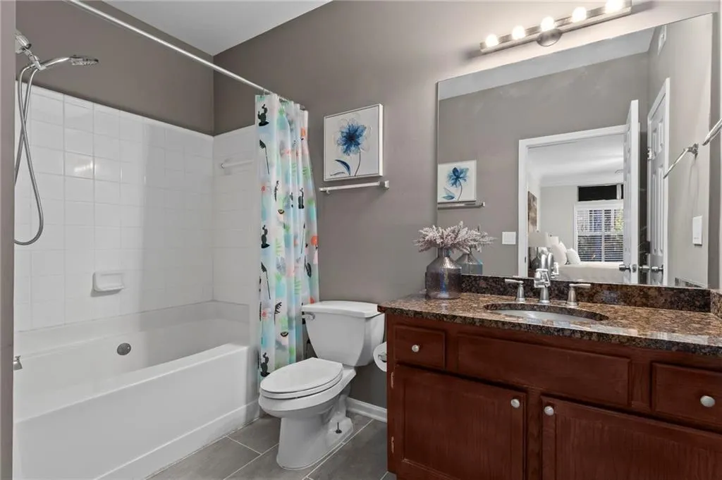 Bathroom featuring shower / tub combo, vanity, light tile patterned floors, and ensuite bathroom