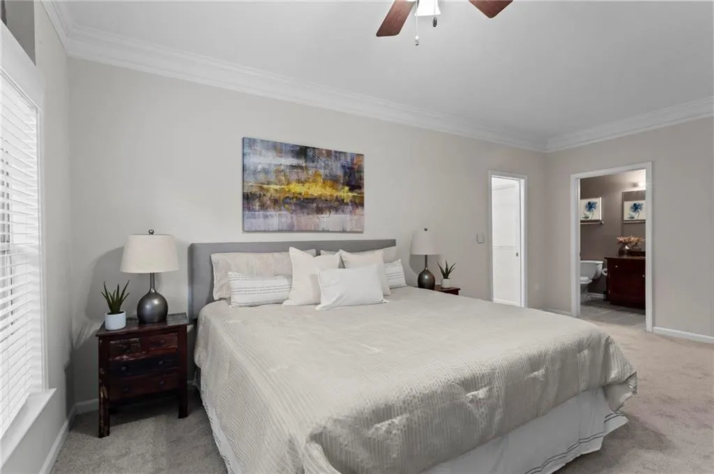 Bedroom with light carpet, crown molding, ceiling fan, and connected bathroom