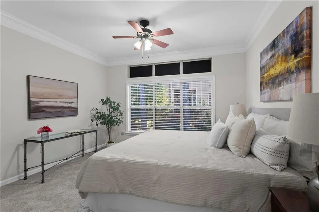 Bedroom with ornamental molding, light carpet, and ceiling fan