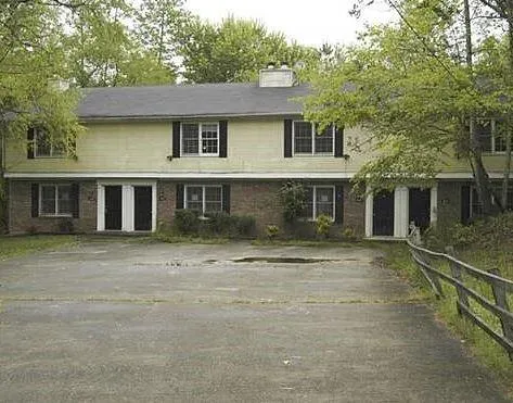 Two-story exterior with brick and siding, featuring multiple windows with dark shutters, and a dark asphalt shingle roof