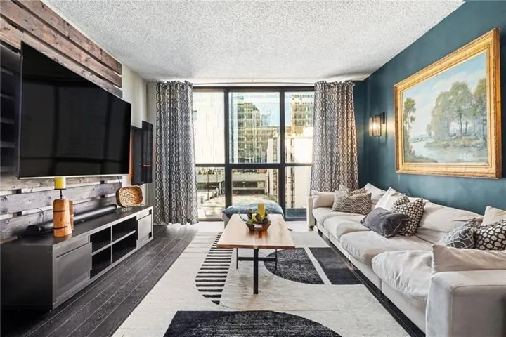 Full-height windows with dark trim, dark wood-finish flooring, accent wall with wood paneling, wall-mounted sconce, and recessed lighting