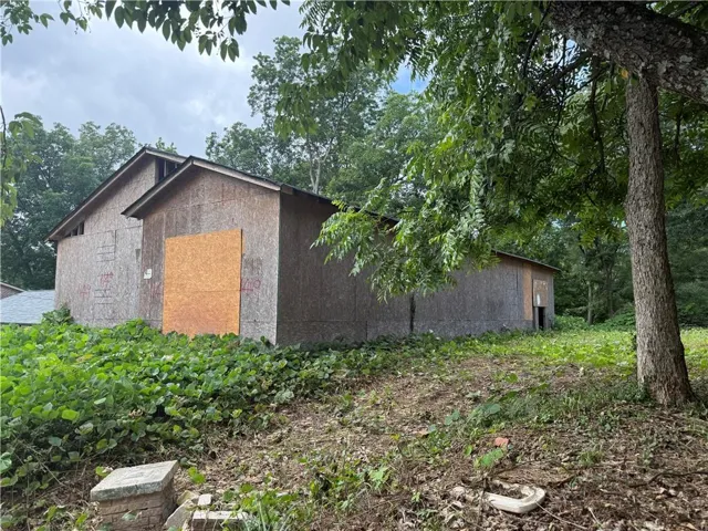 Wood-paneled outbuilding with a pitched roof and a boarded-up opening