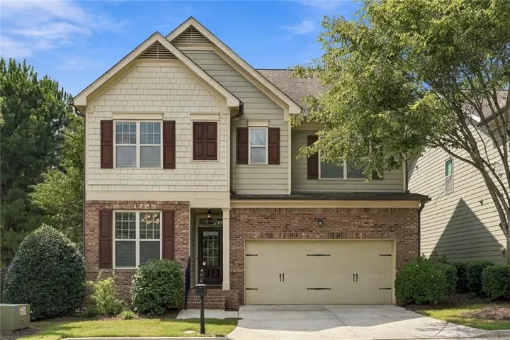 Two-story exterior with brick and siding facade, covered front entry, attached two-car garage, and established landscaping